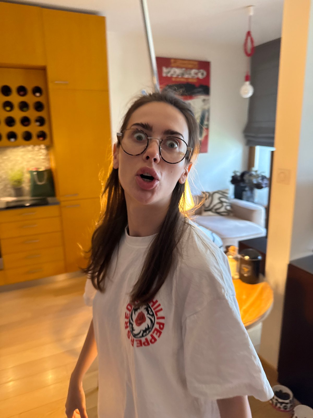 Woman in white shirt captured across kitchen and workspace