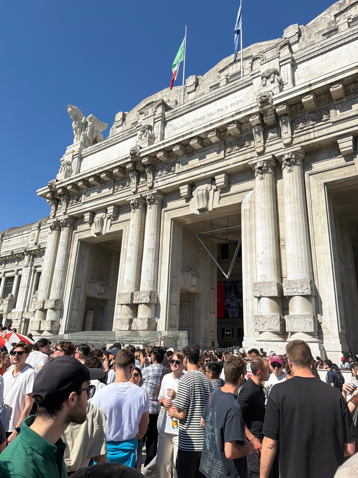 Crowds gather at Milan Central Station's neo-classical facade