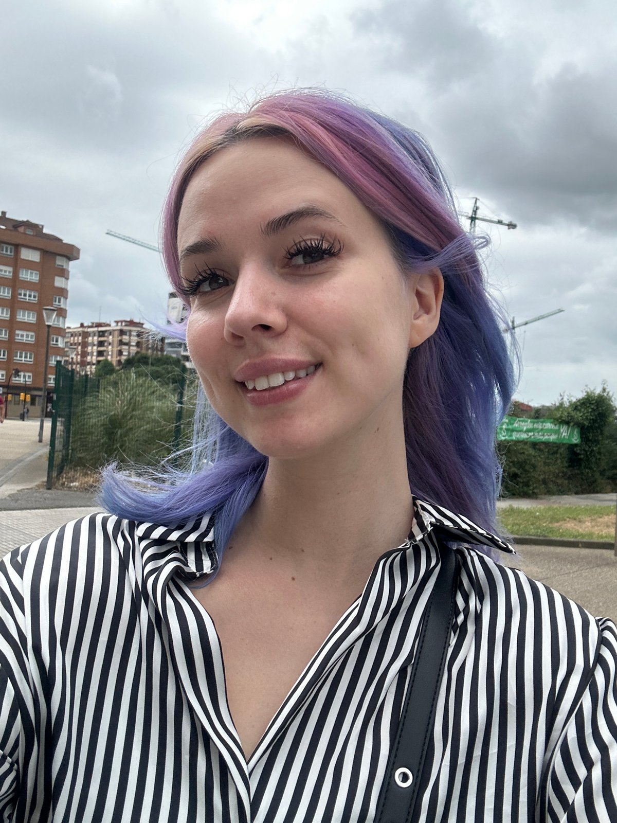 Woman takes colorful selfies in overcast Gijón cityscape