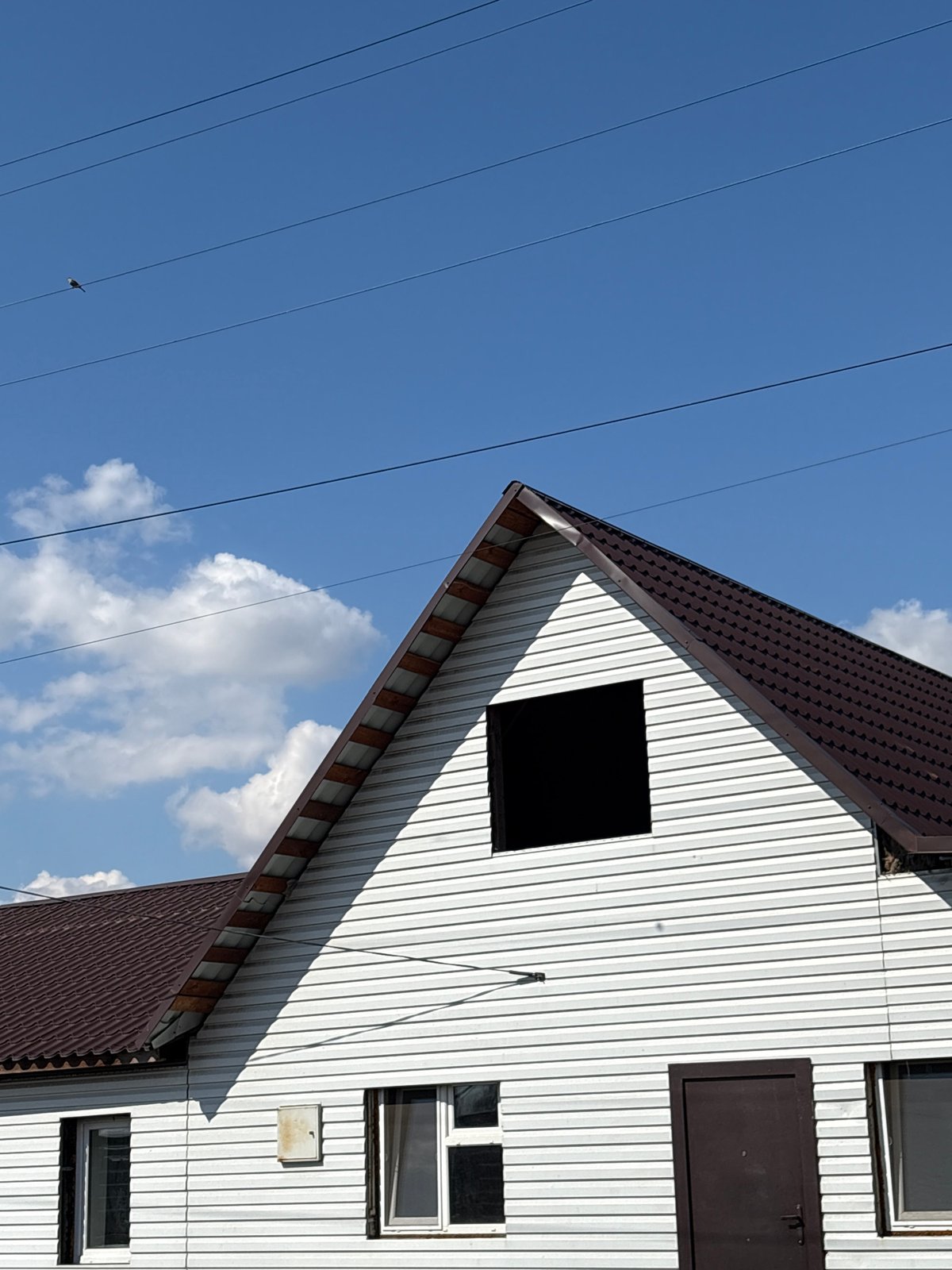 White building with brown roof documented under blue sky
