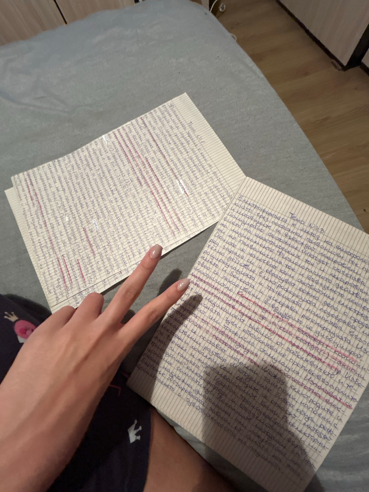 Person displays peace sign while holding handwritten notes on bed
