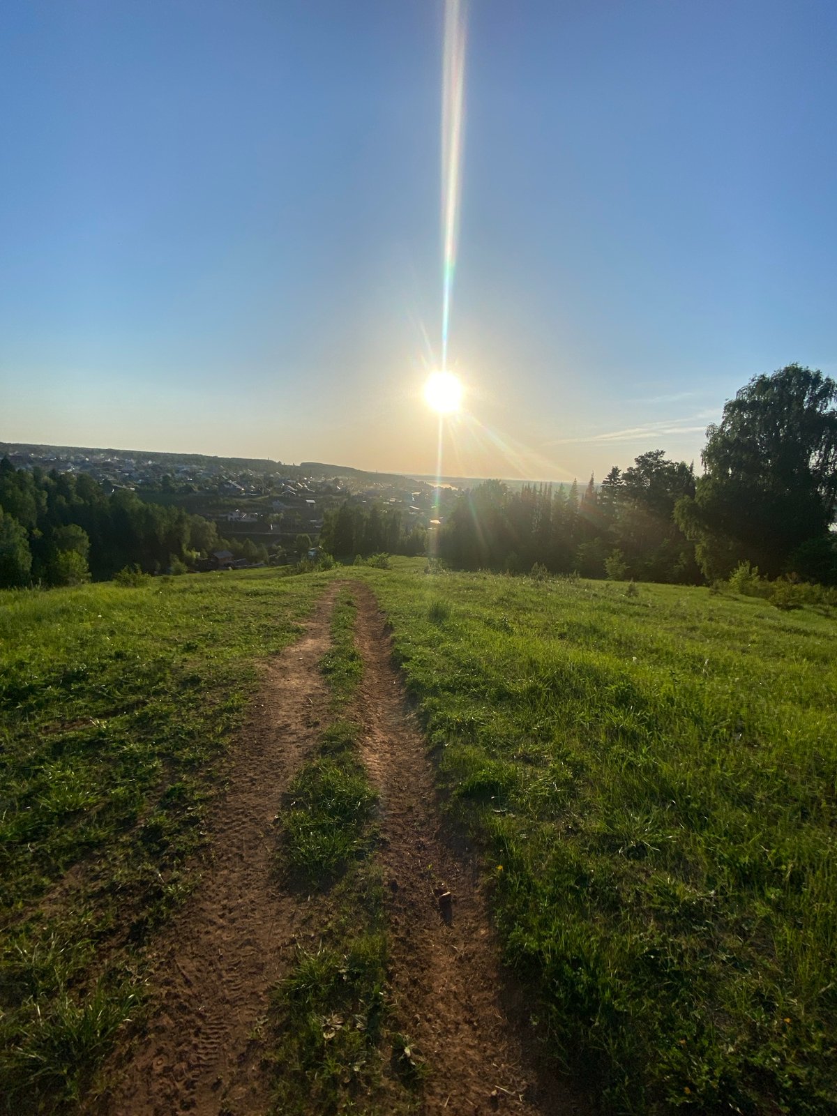 Hillside path overlooks Ольховка under low afternoon sun