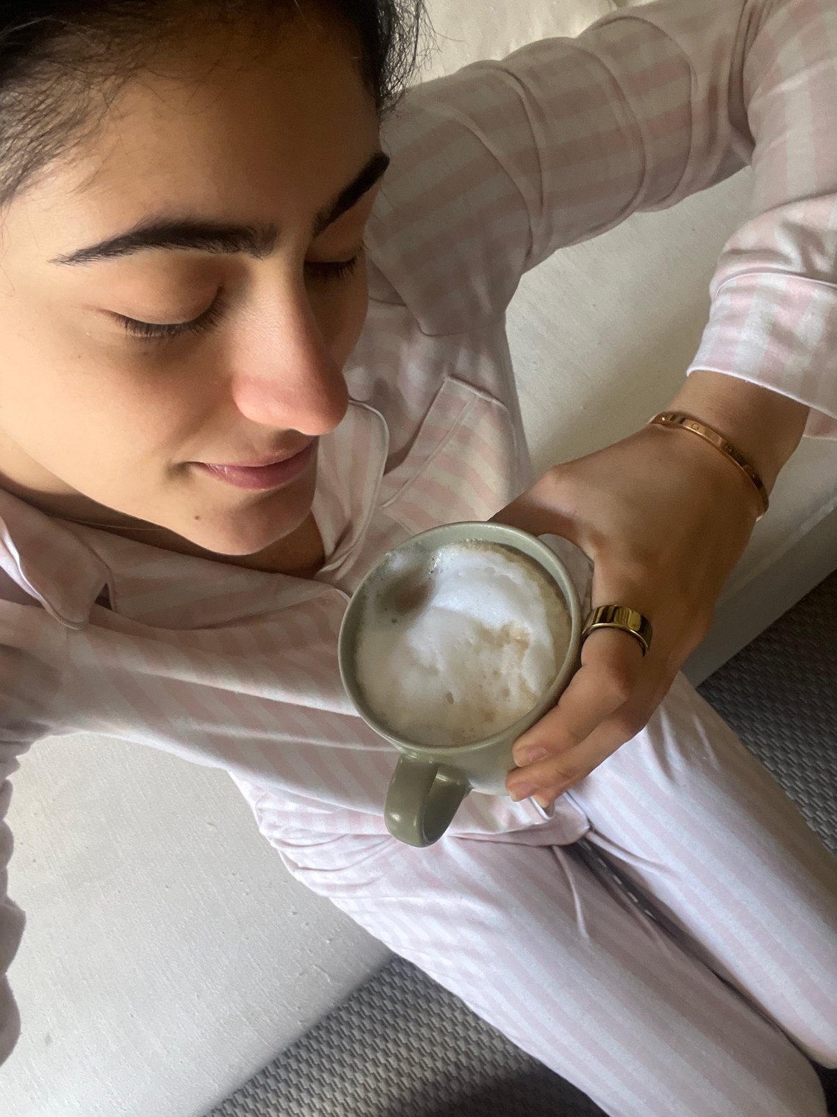 Woman enjoys breakfast in bed with latte and yogurt bowl