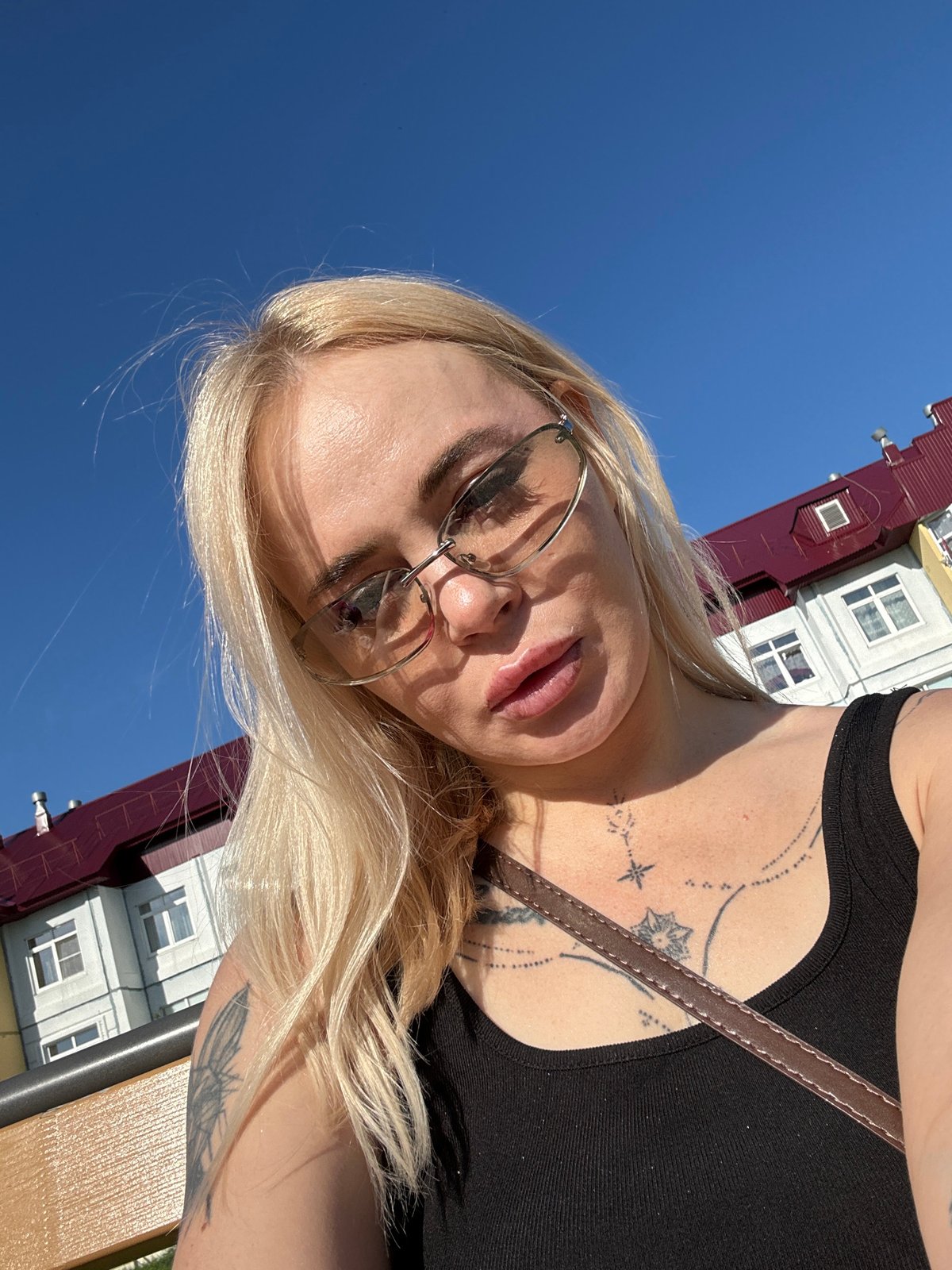 Woman takes selfies near colorful building during midday break