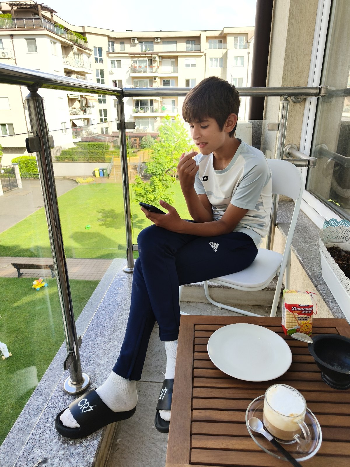 Child sits on balcony chair in Sofia afternoon