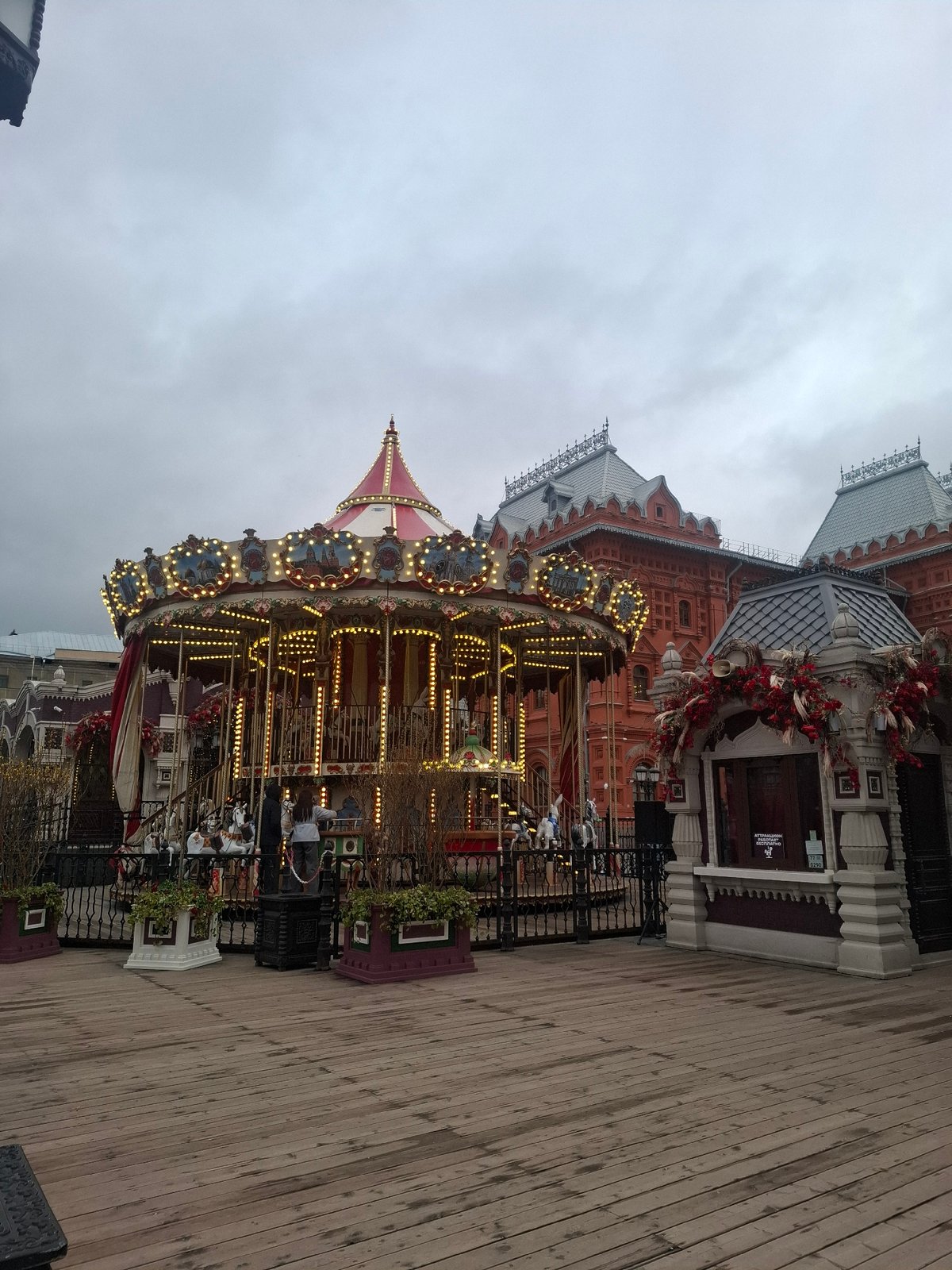 Illuminated carousel operates in Moscow square amid overcast afternoon