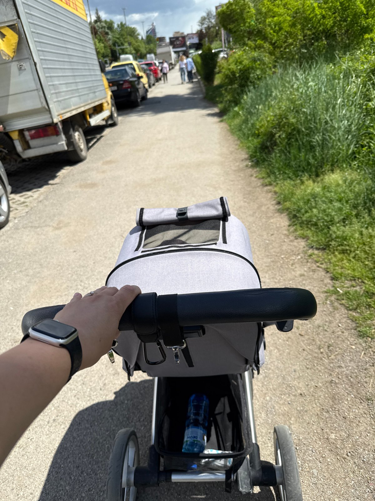 Parent pushes stroller along Sofia street amid parked vehicles