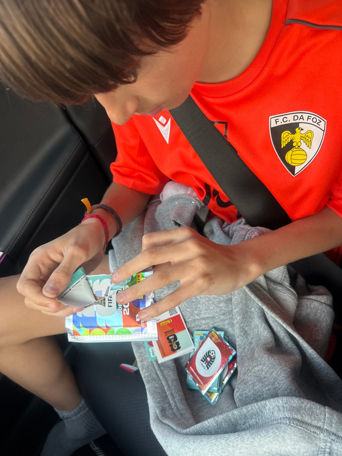 Child opens World Cup stickers during sunset in Portugal