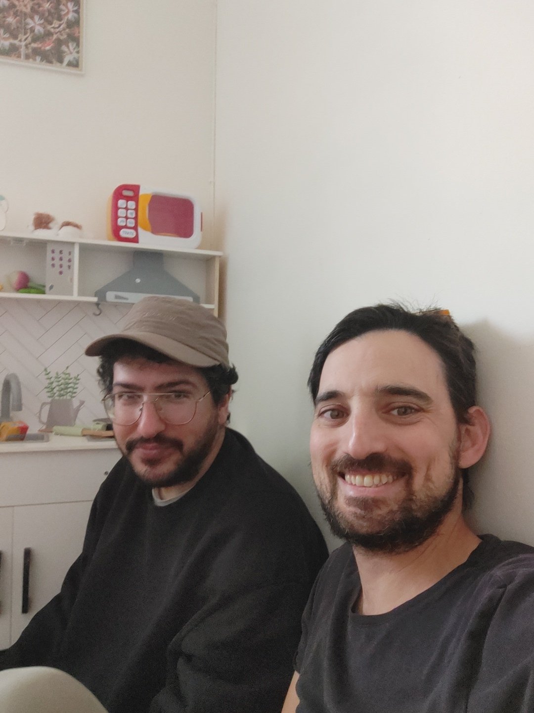 Two men photographed together in casual indoor setting