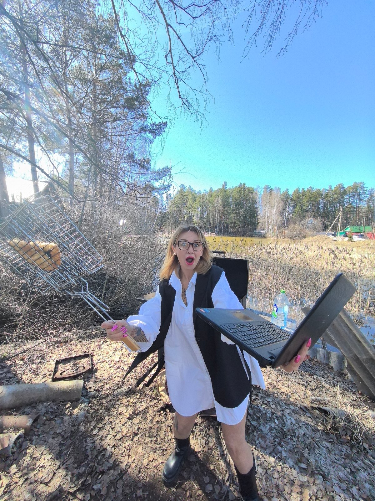 Woman multitasks with laptop while outdoor cooking in Russia