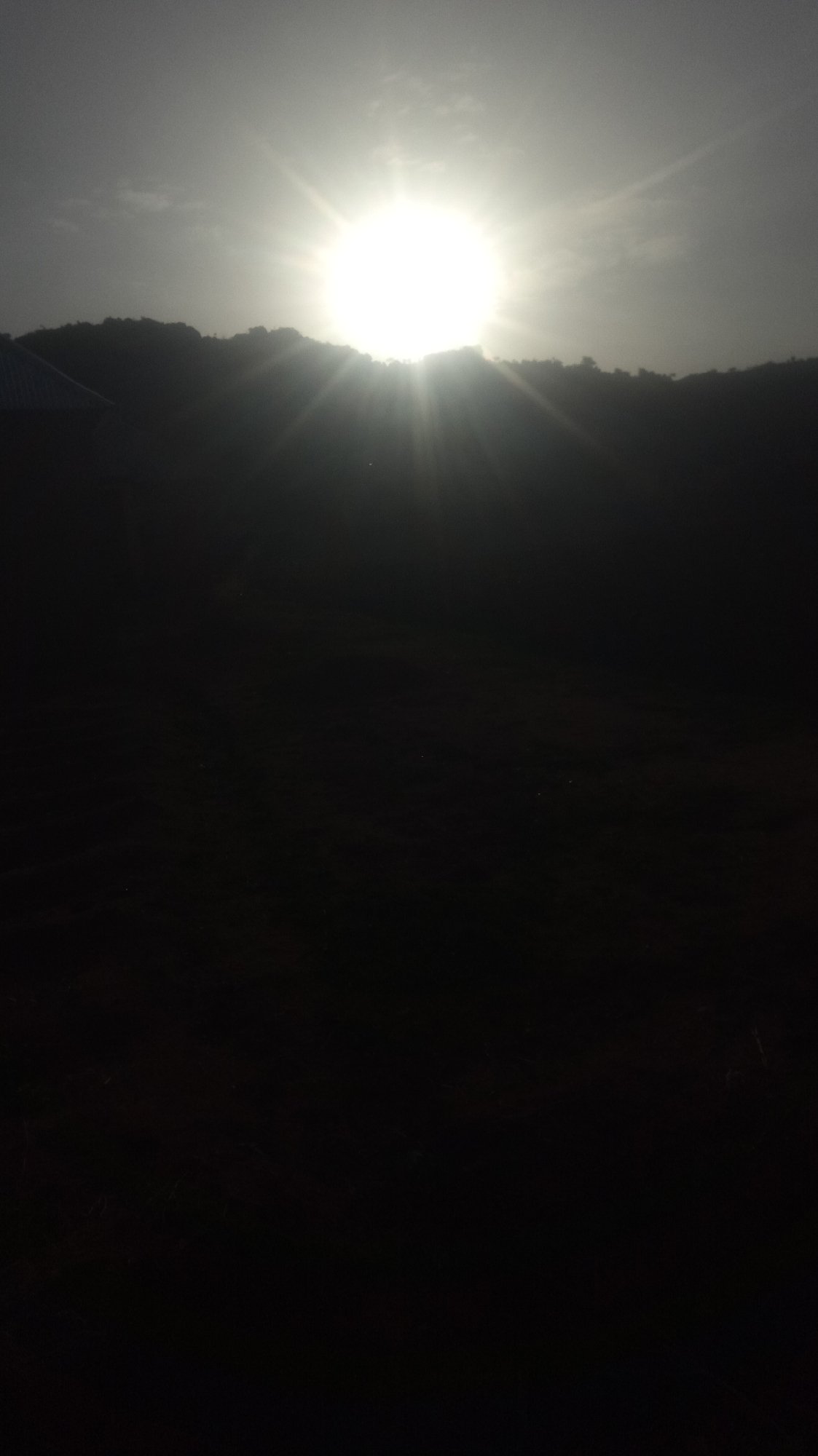 Dawn sunlight captured through silhouetted landscape with building visible