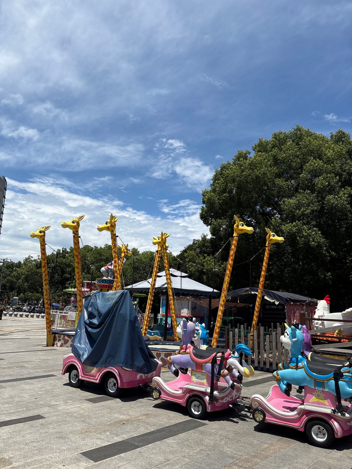 Minhang street scene: amusement rides, vendors, and a cartoon-wrapped Tesla