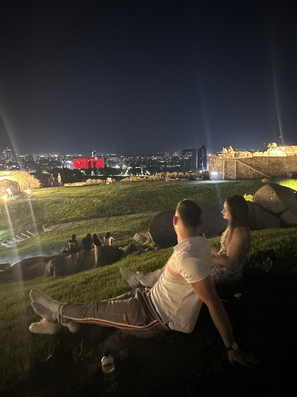 Evening gathering overlooks illuminated Plovdiv cityscape from hillside vantage point