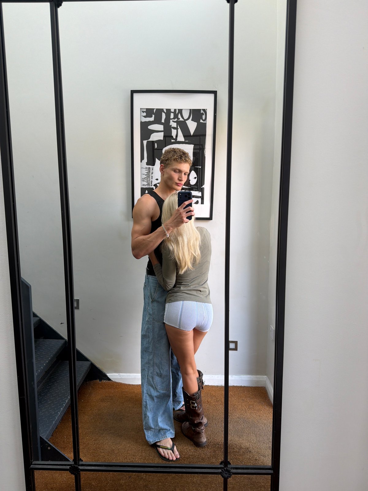 Mirror selfie in a London residential hallway, casual pose.