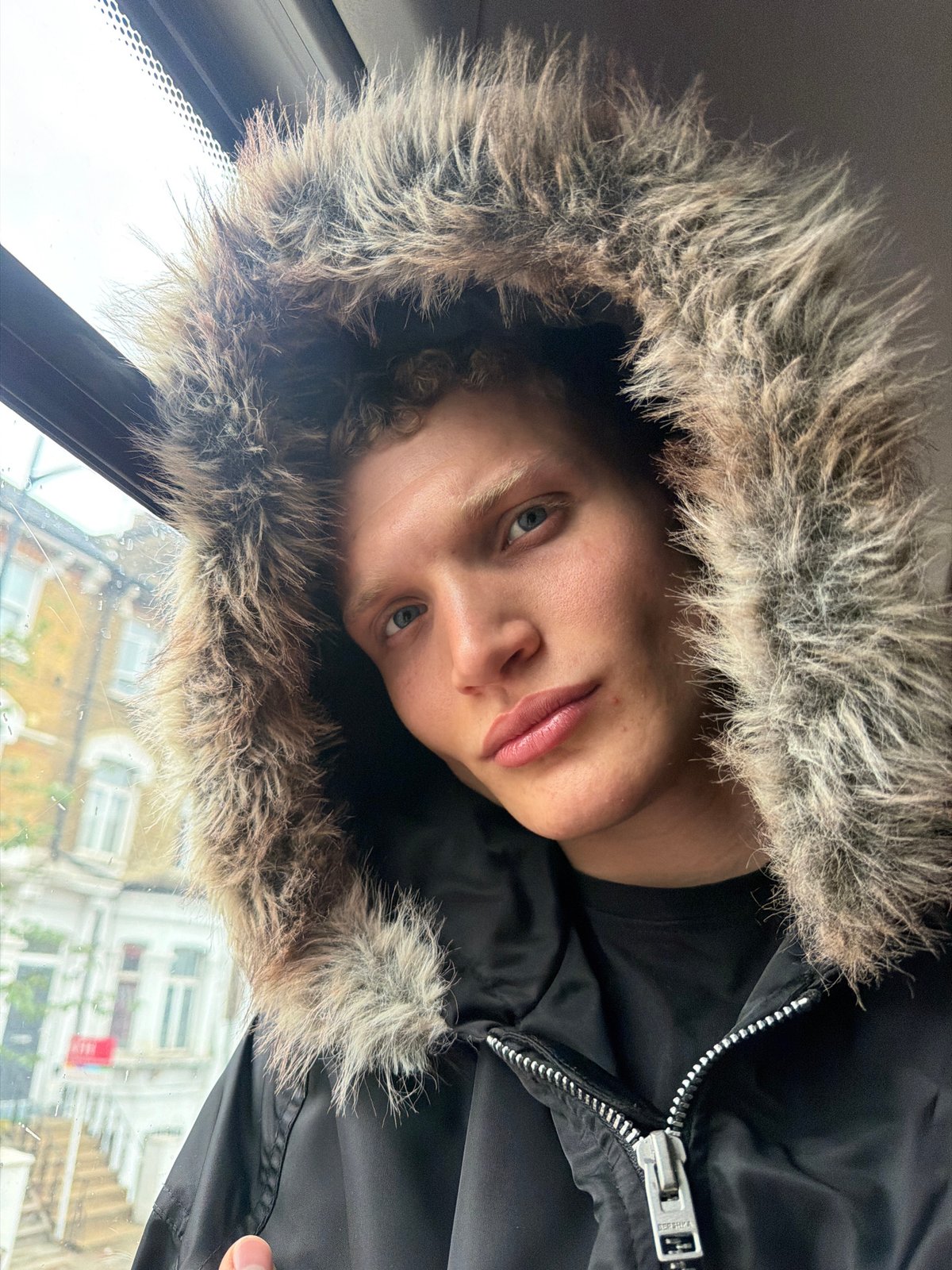 Young person in fur-trimmed hood photographed in London selfie