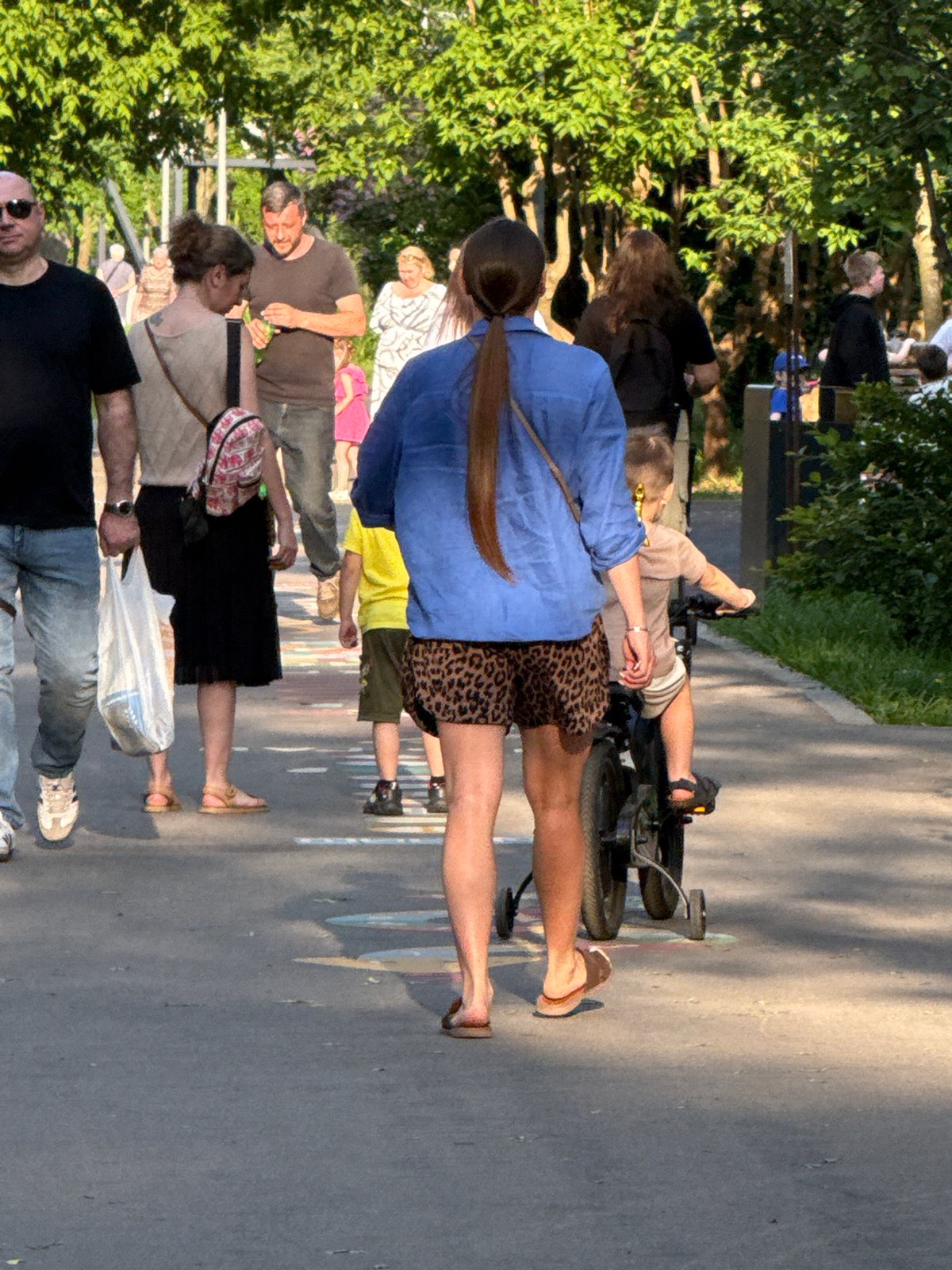 Mixed-age group strolls through Moscow park in summer attire