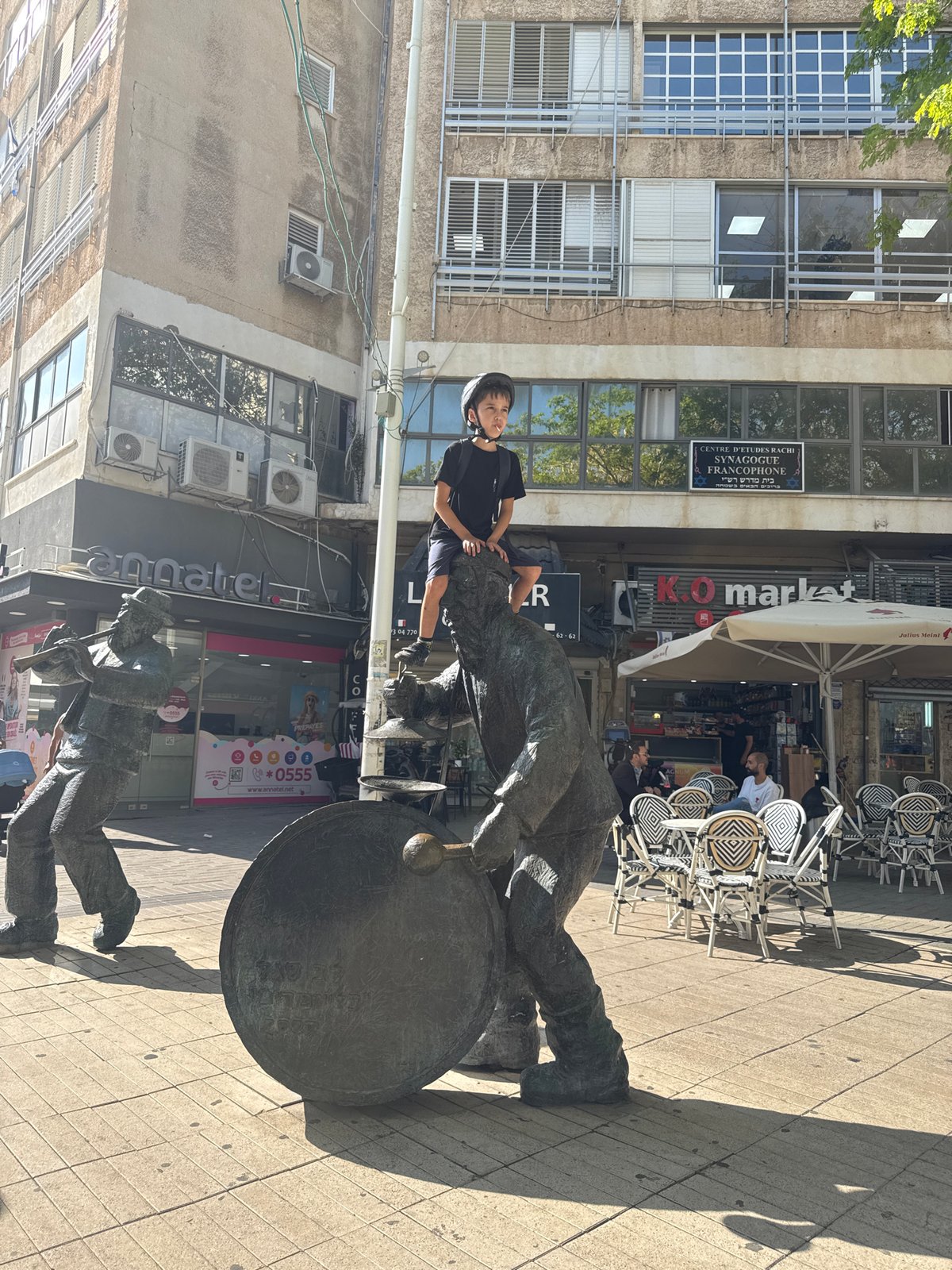 Child plays among bronze musician statues in Netanya square