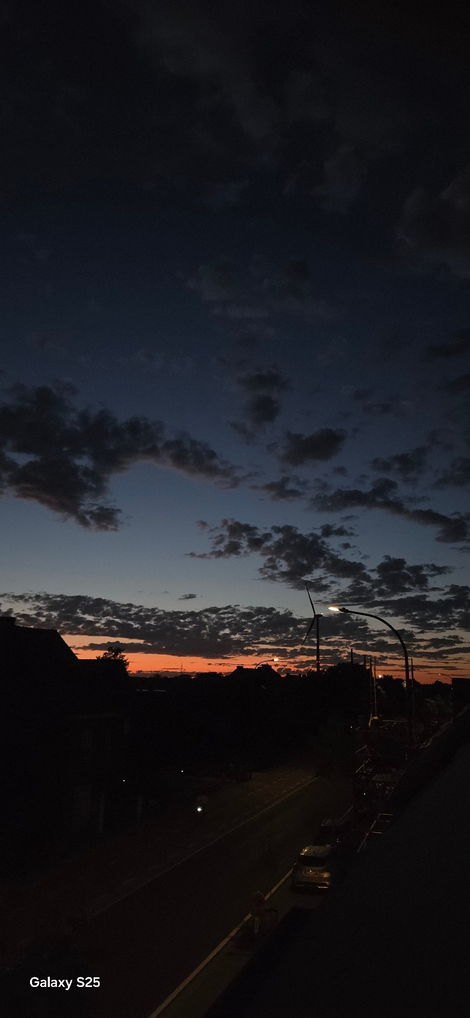 Sunset to twilight: wind turbine and suburban skyline at dusk