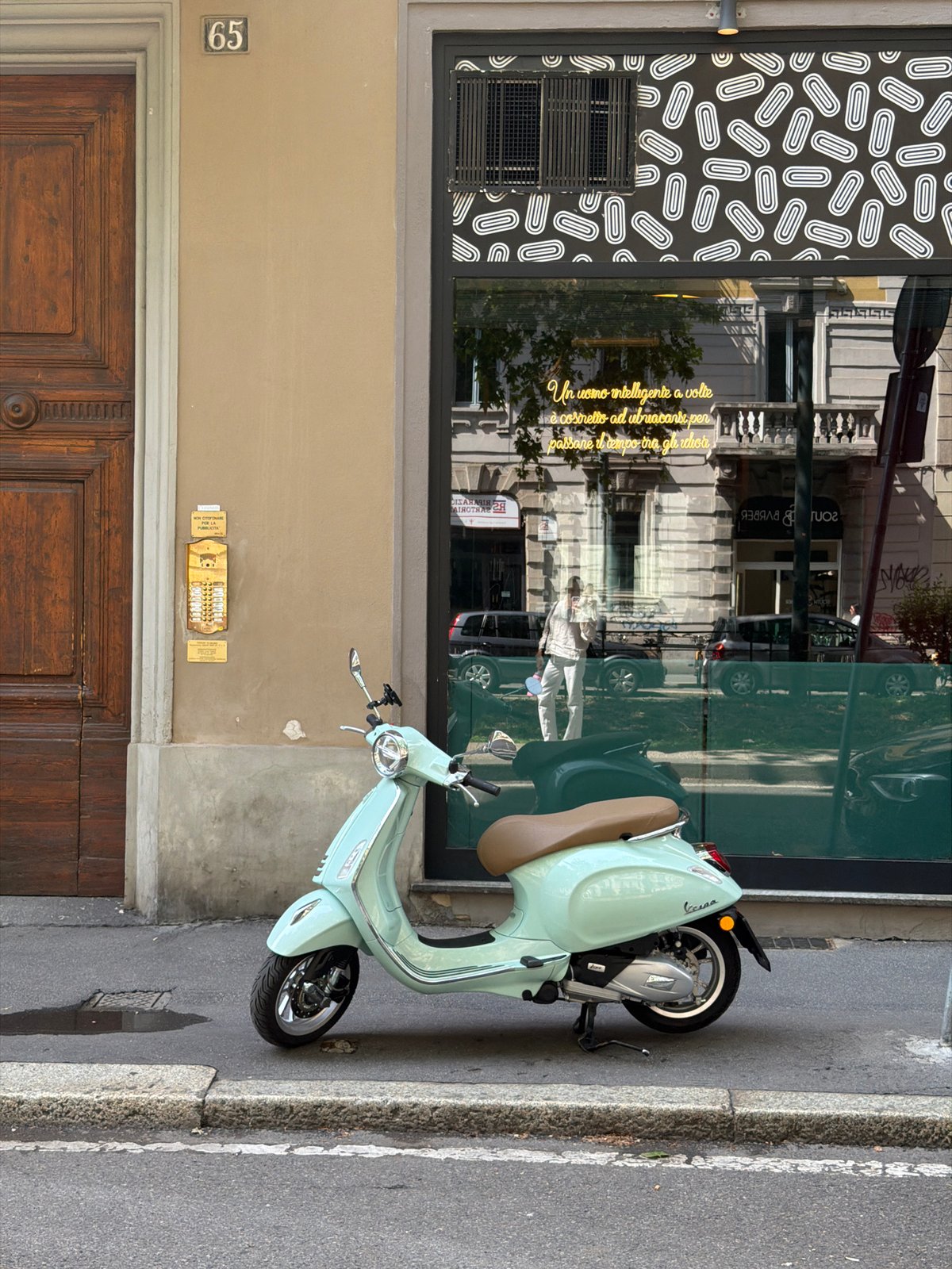 Milan street scene features parked scooter, car near café