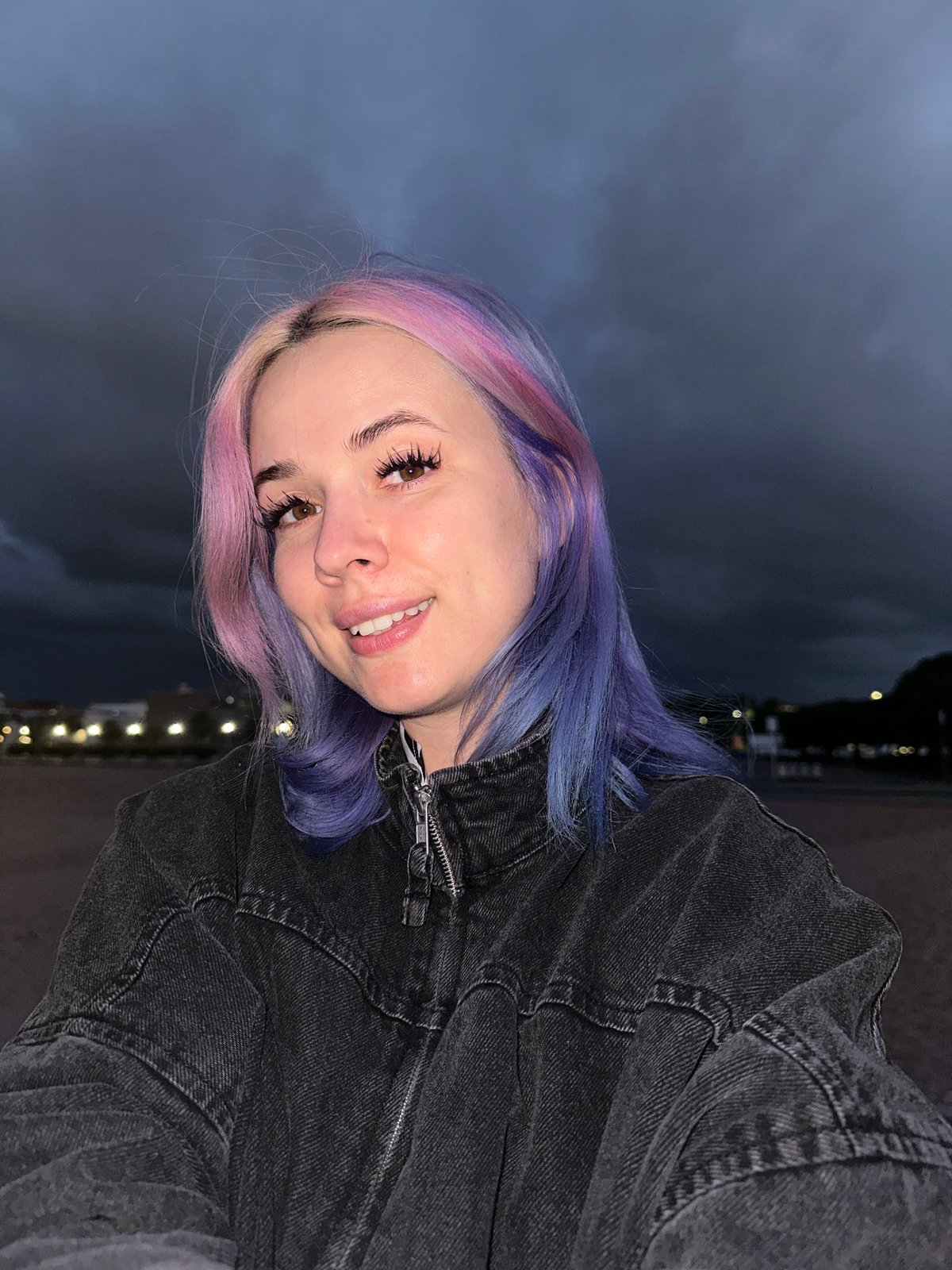 Woman with colorful hair visits Gijón beach at dusk