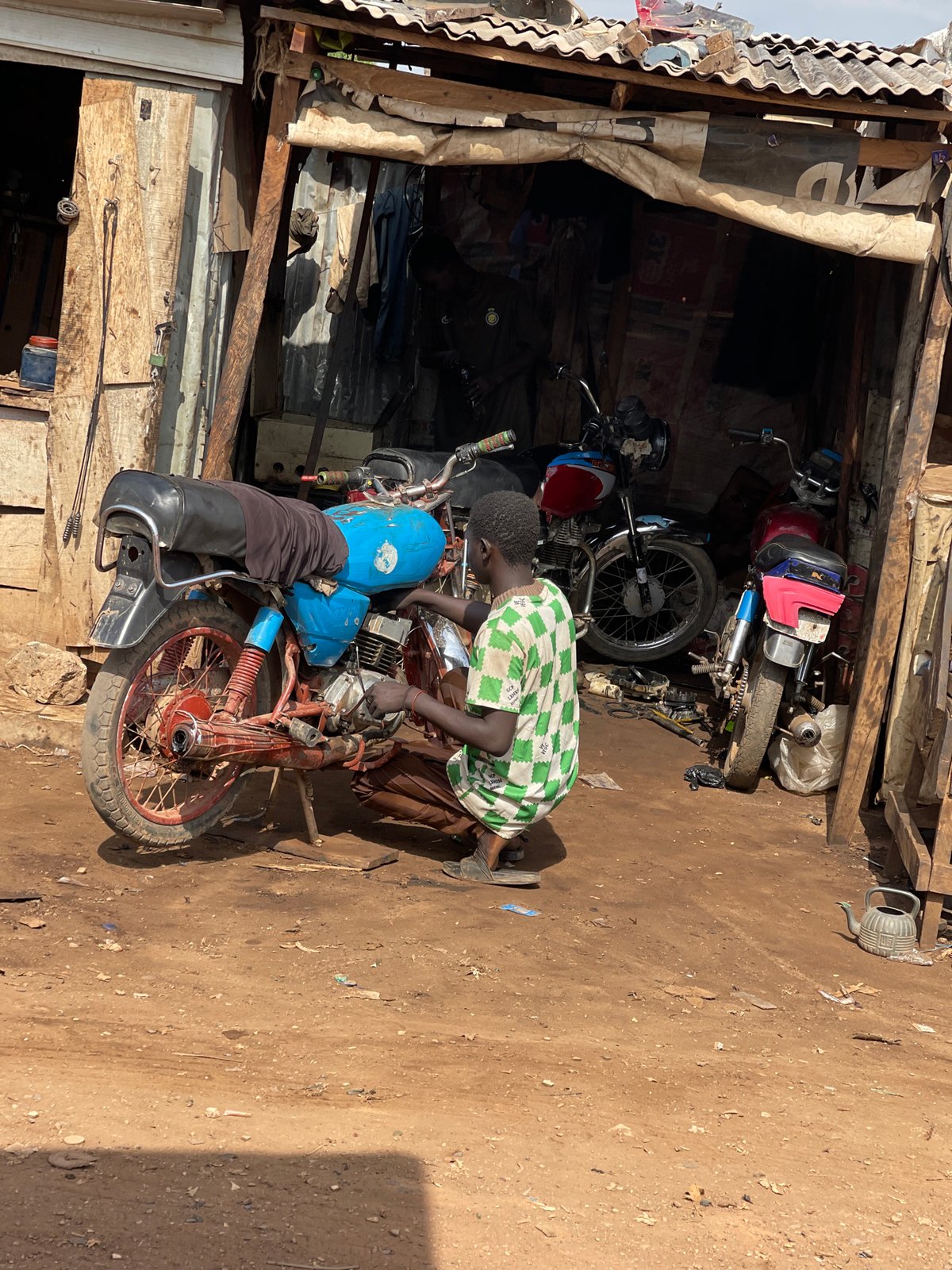 Outdoor metalworking and motorcycle repair operations documented in Abuja