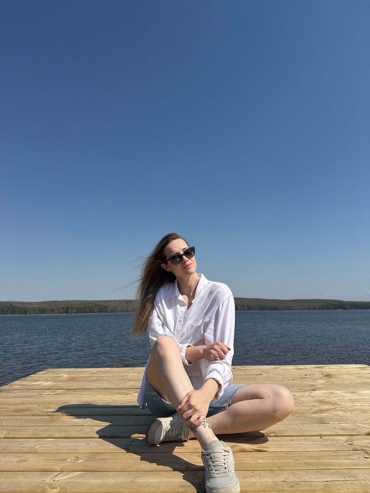 Woman enjoys morning moments on wooden pier in Chaikovsky