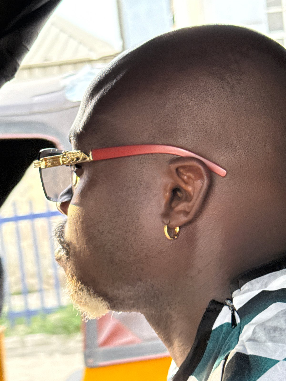 Man with gold earrings, red sunglasses photographed in Ikorodu