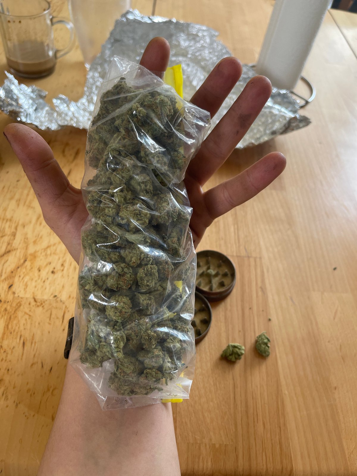 Individual observed preparing cannabis materials with various paraphernalia indoors
