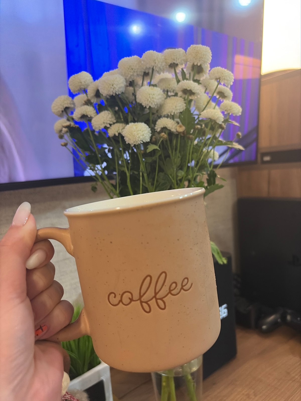 Person holds flowers and coffee mug in Chaikovsky, Russia