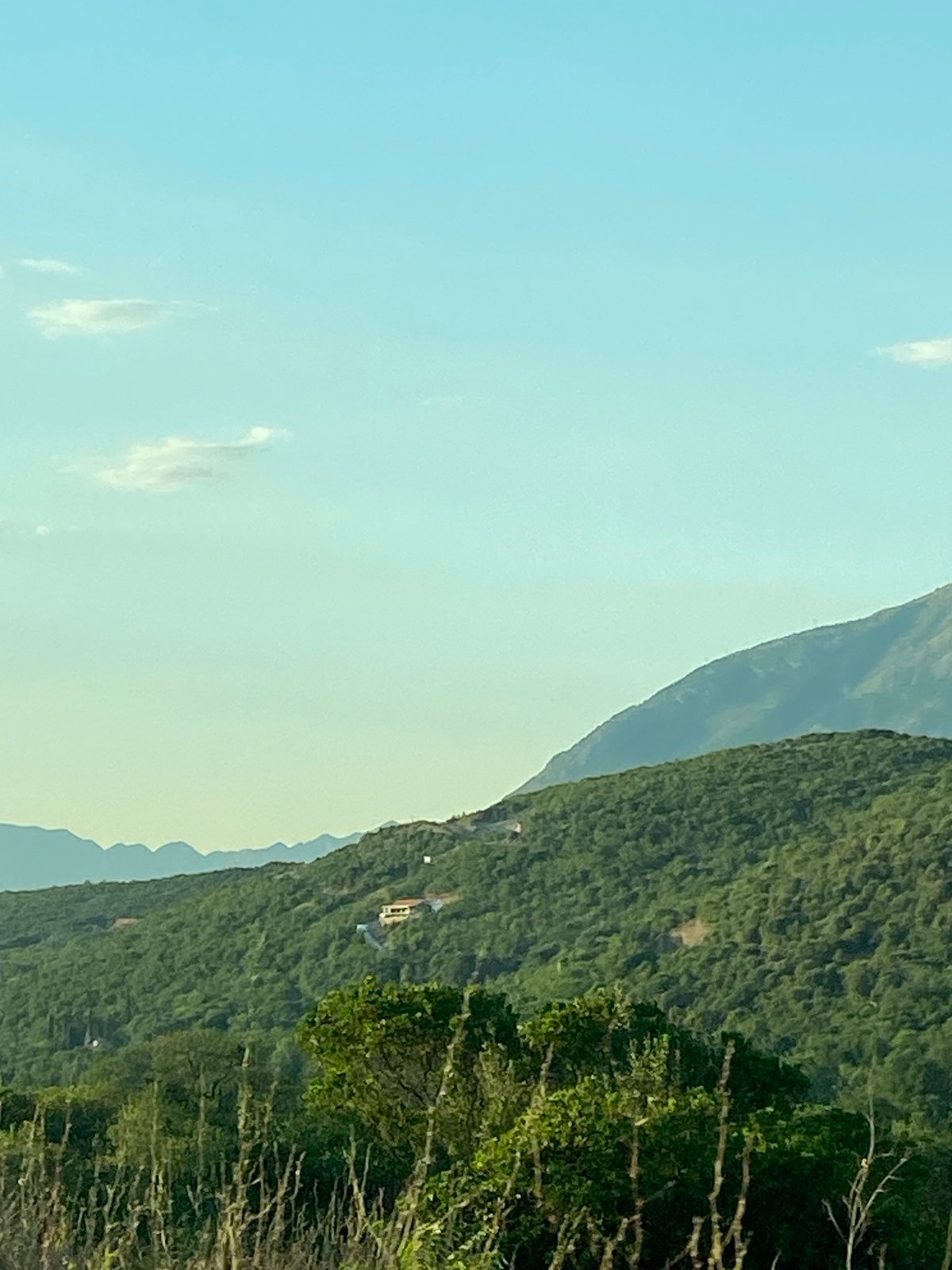 Plane crosses clear skies above Montenegro's green hills