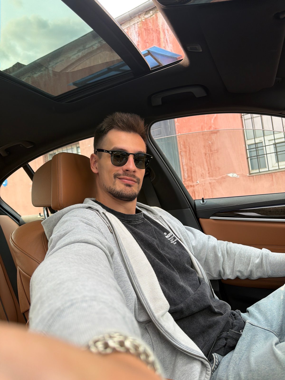 Car selfies in Krasnoyarsk, sunroof open, brick building outside