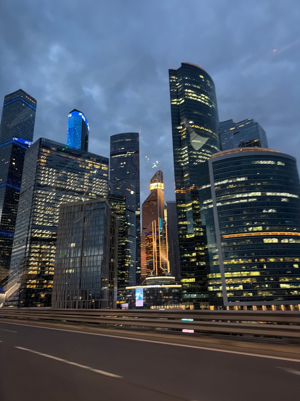 City skyscrapers glow against a dark cloudy night sky.