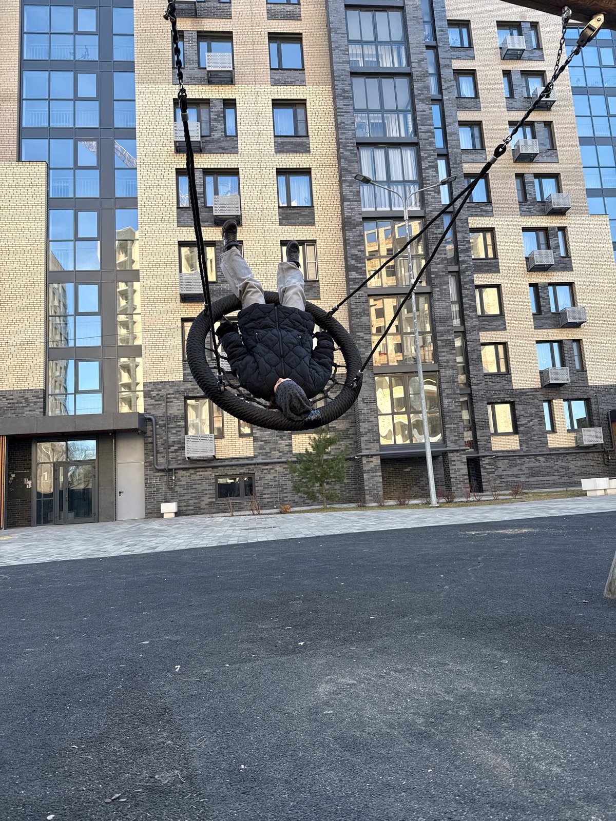 Child plays on swings at Rusanovo apartment complex playground