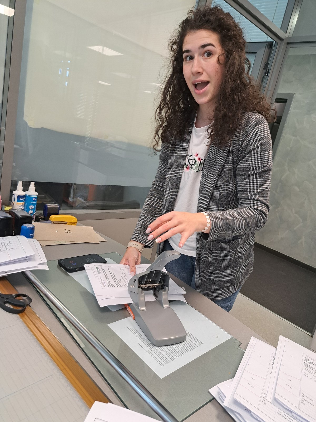 Woman operates paper punch in office setting