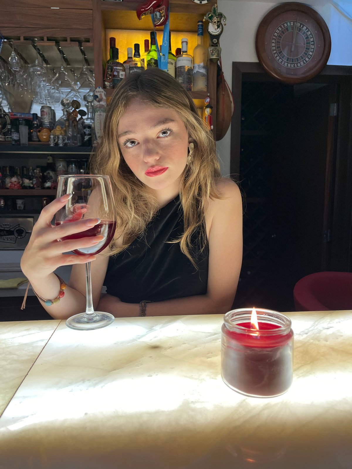 Woman photographed at bar in Mexico holding drinks, candle