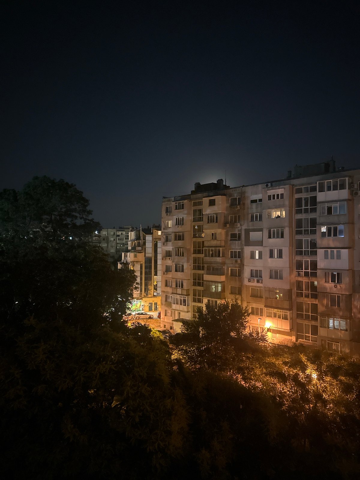 Nighttime views of a concrete apartment building under a full moon