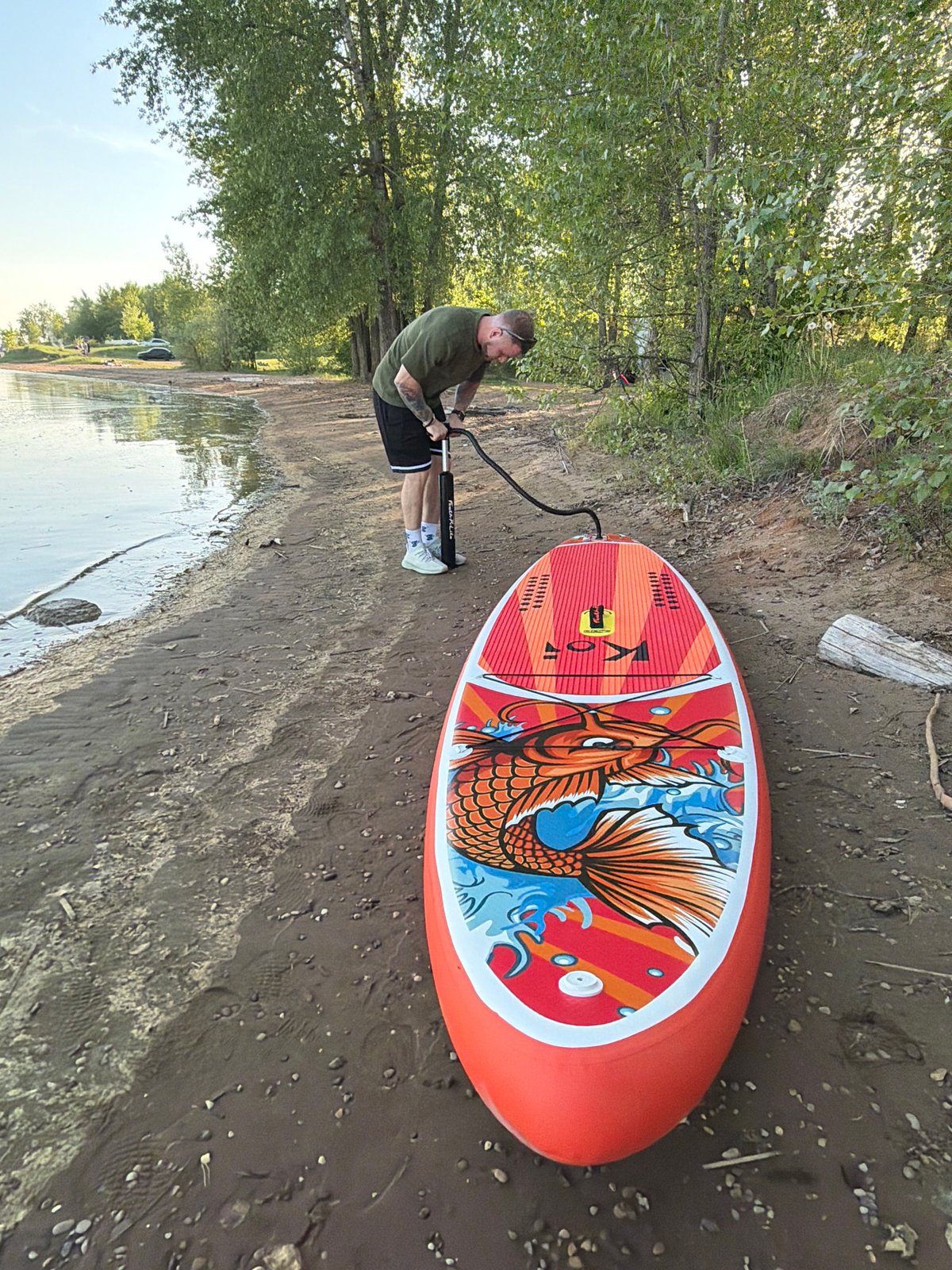 Paddleboarder prepares koi-decorated SUP on Russian shoreline