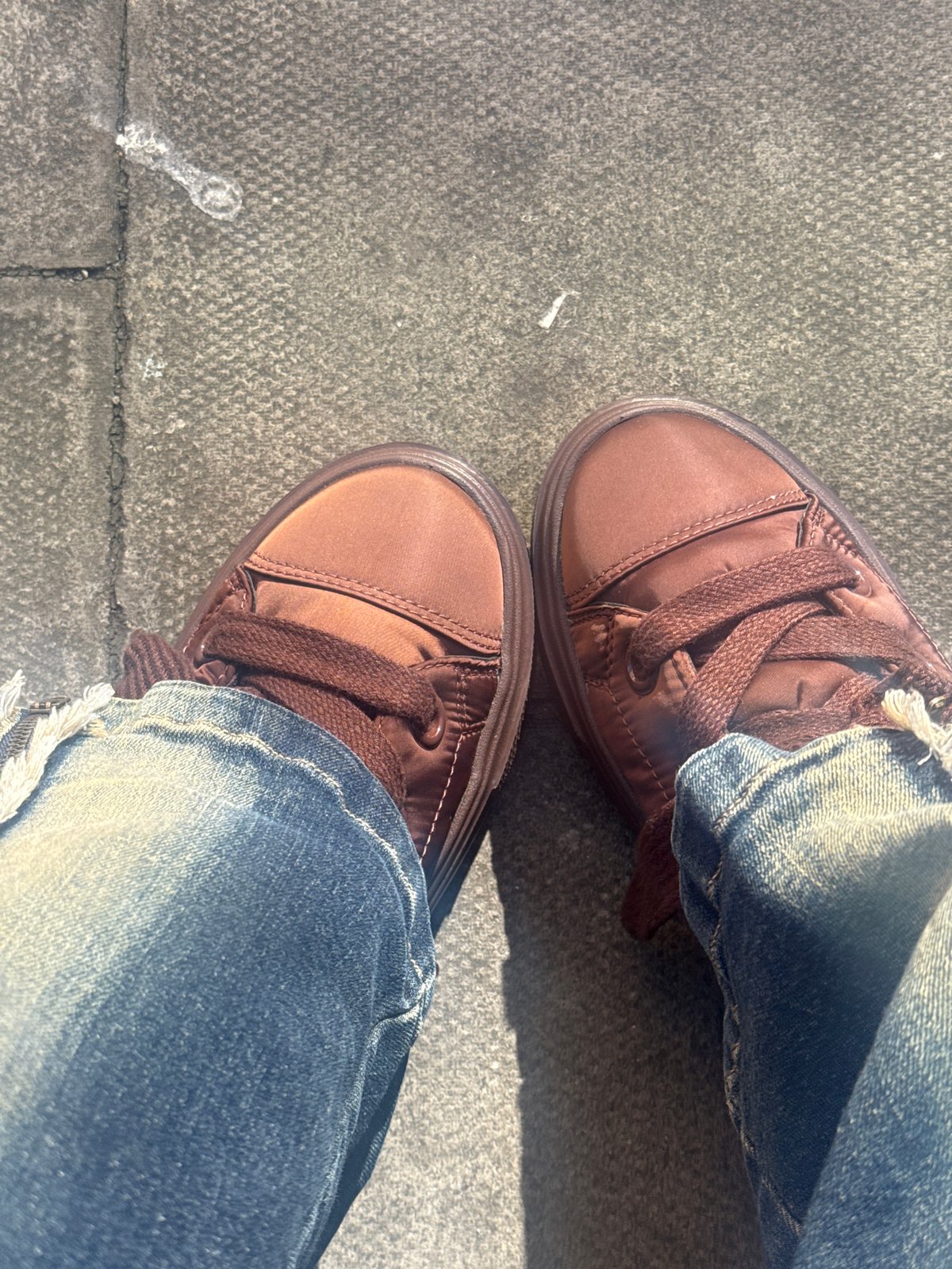 Person in casual shoes stands on London sidewalk