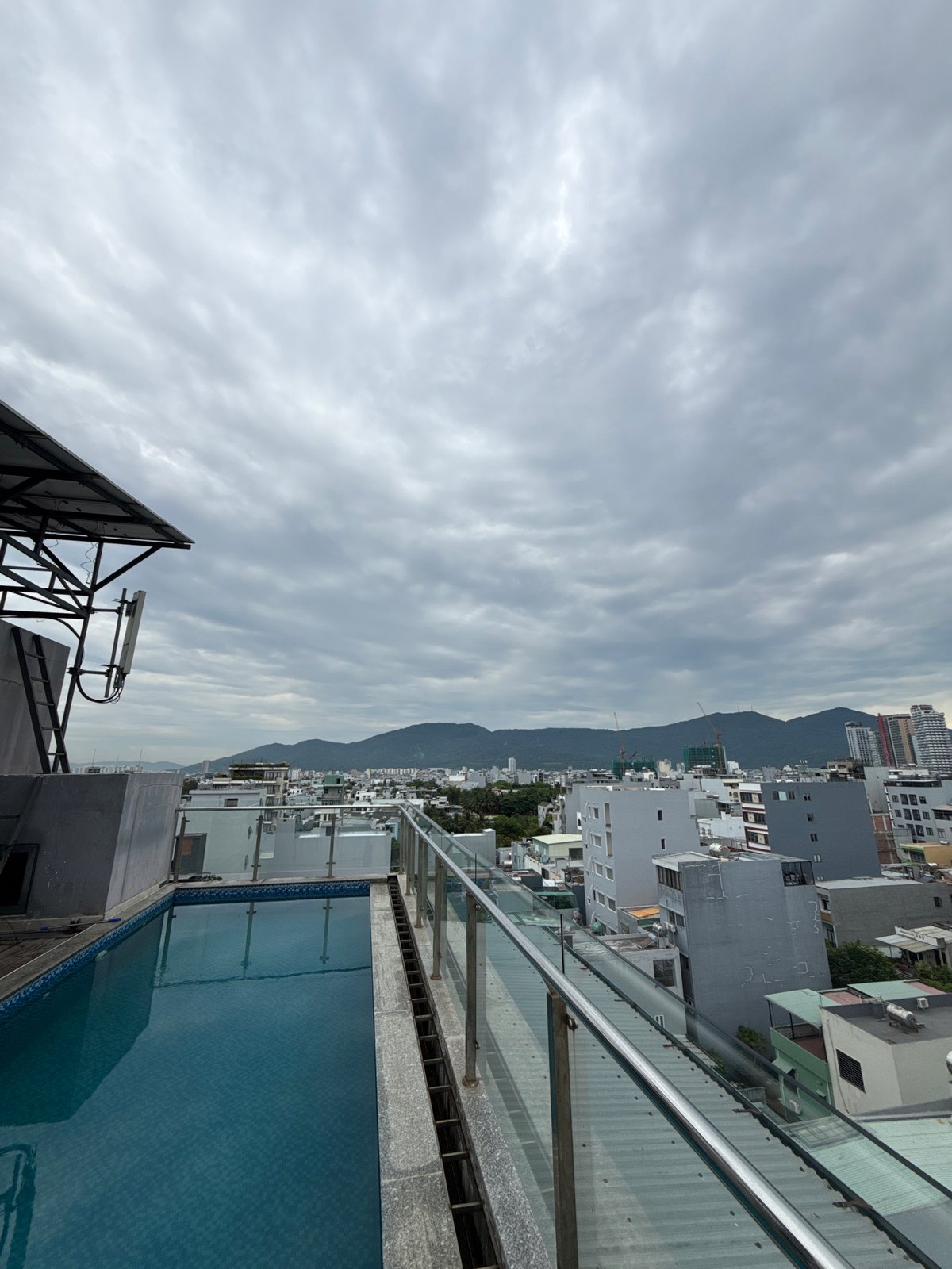 Tattooed visitor documents rooftop pool experience in Đà Nẵng cityscape