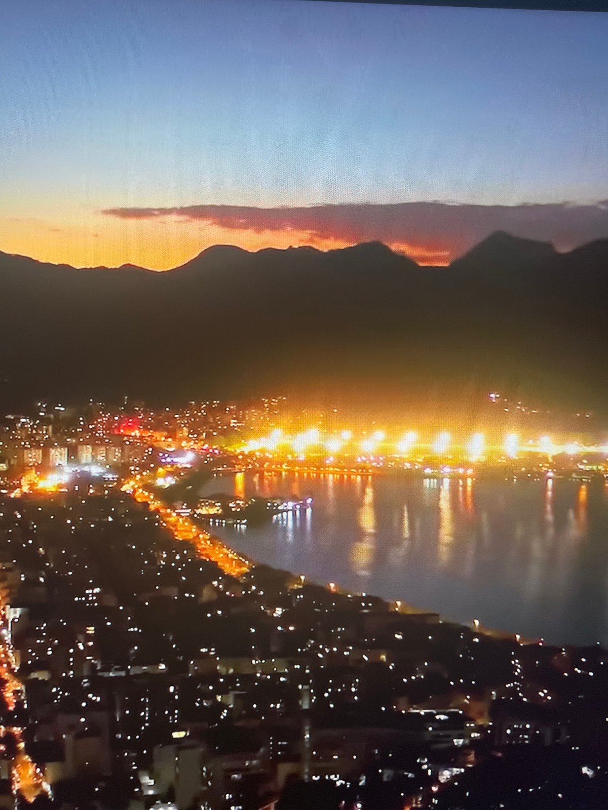 Aerial views document city skyline transition from dusk to night