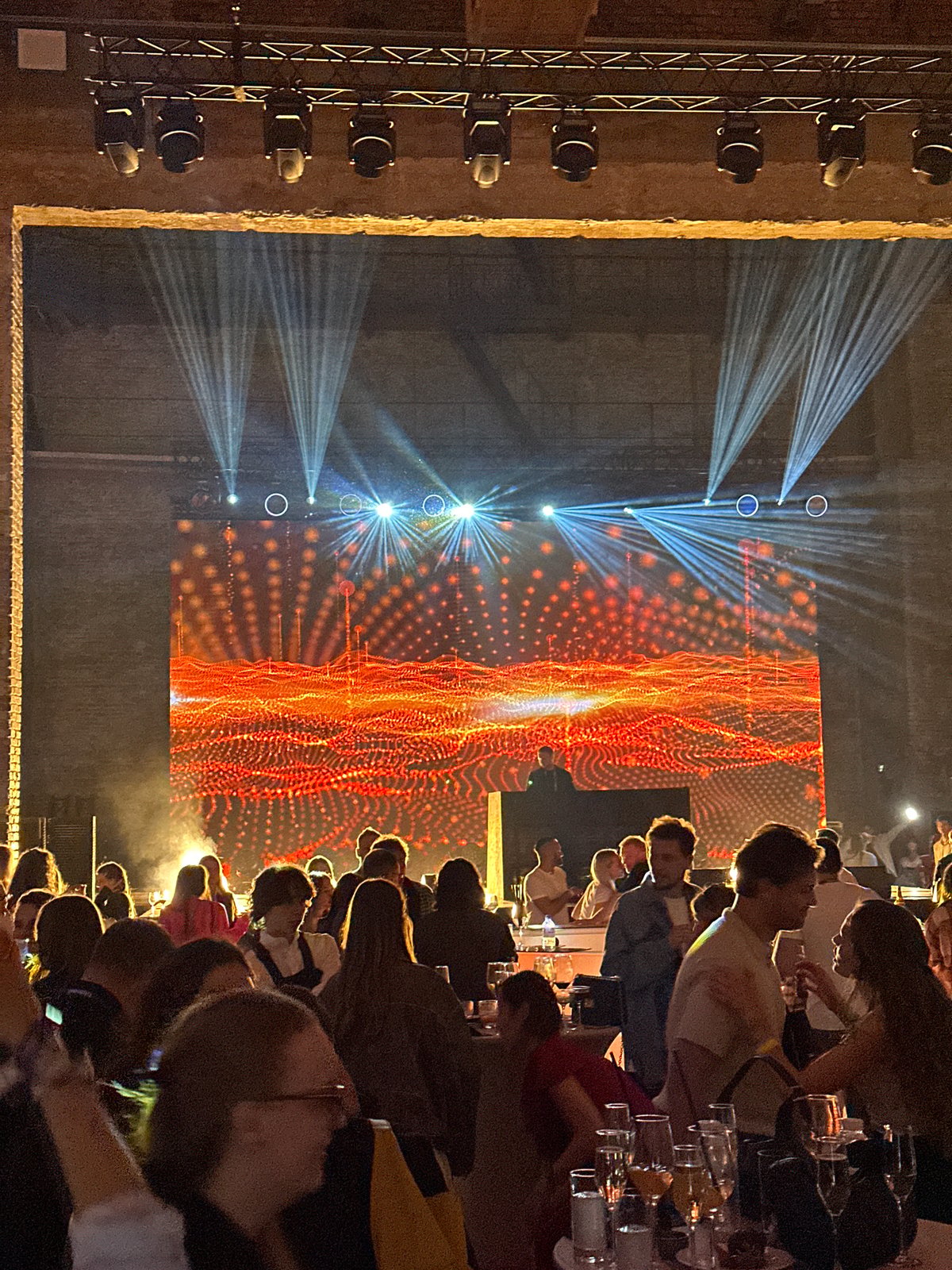 Indoor evening party with stage, crowd, and celebratory atmosphere