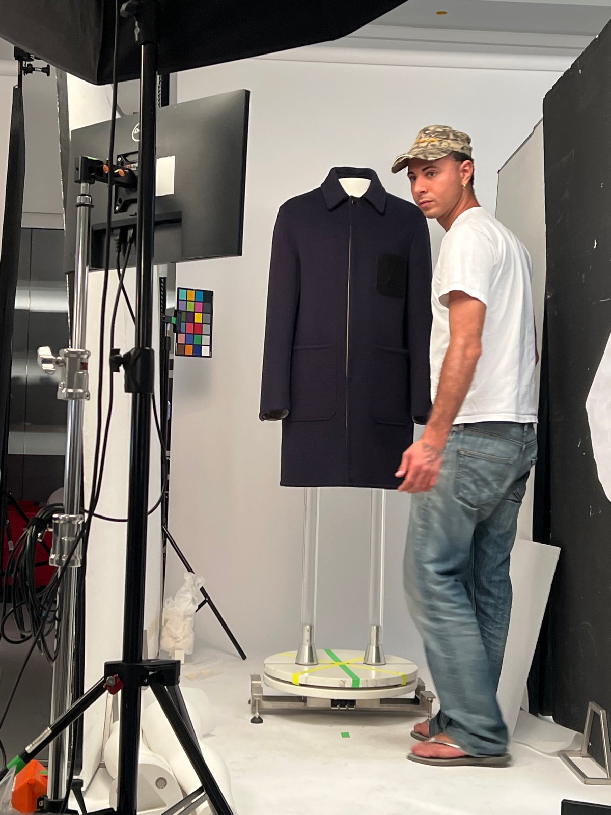 Man photographs navy jacket in professional studio setting