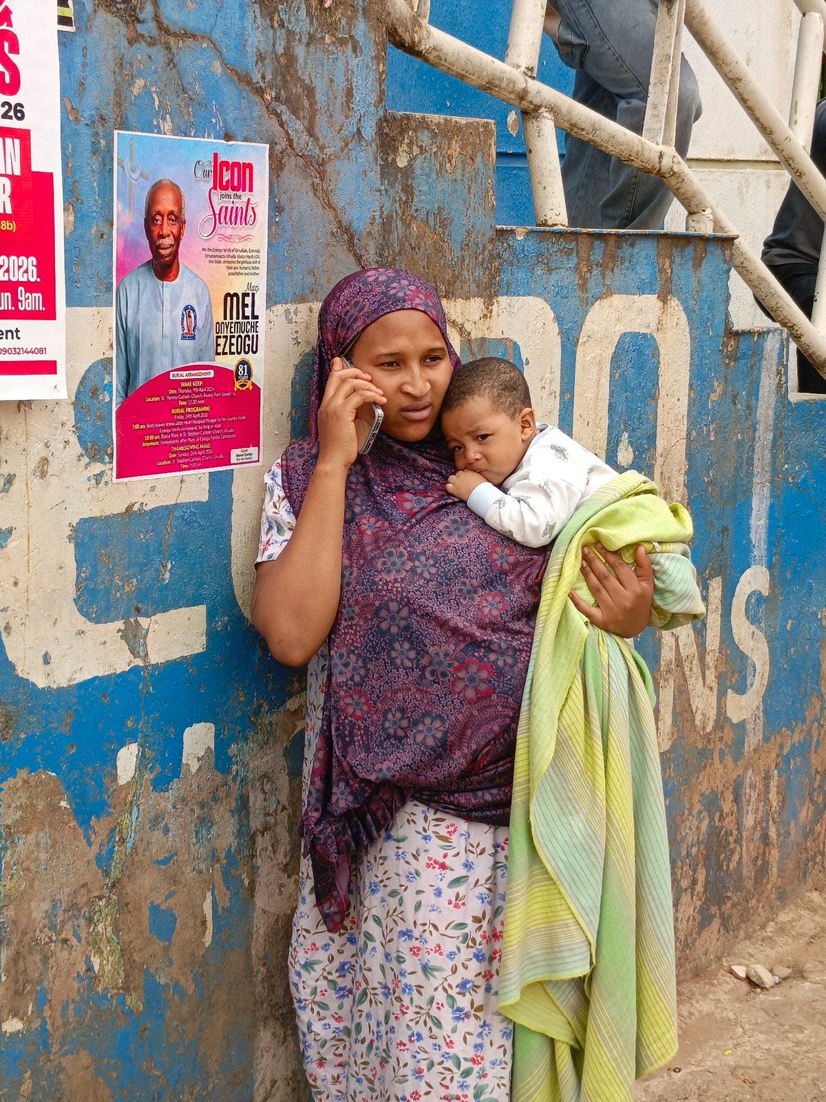 Woman with baby makes phone call against blue wall