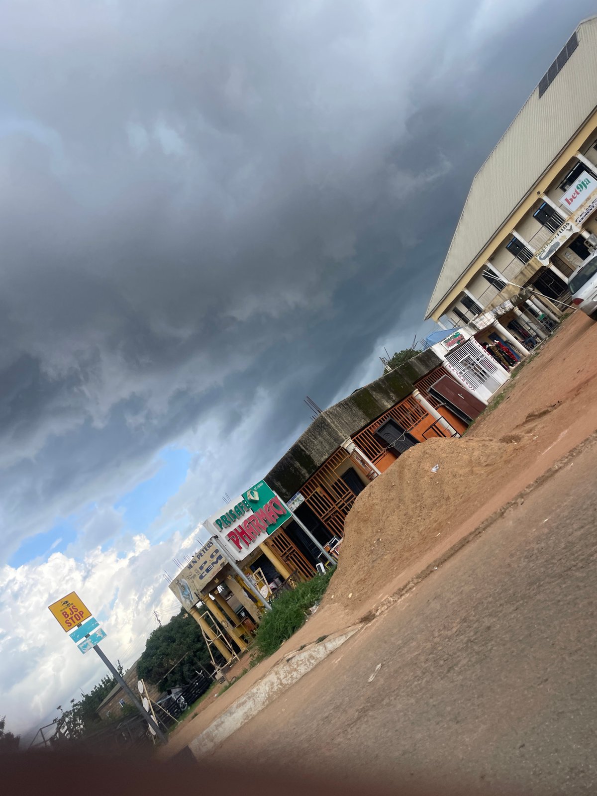 Stormy skies over Gura Top streets, goats and signage in Jos