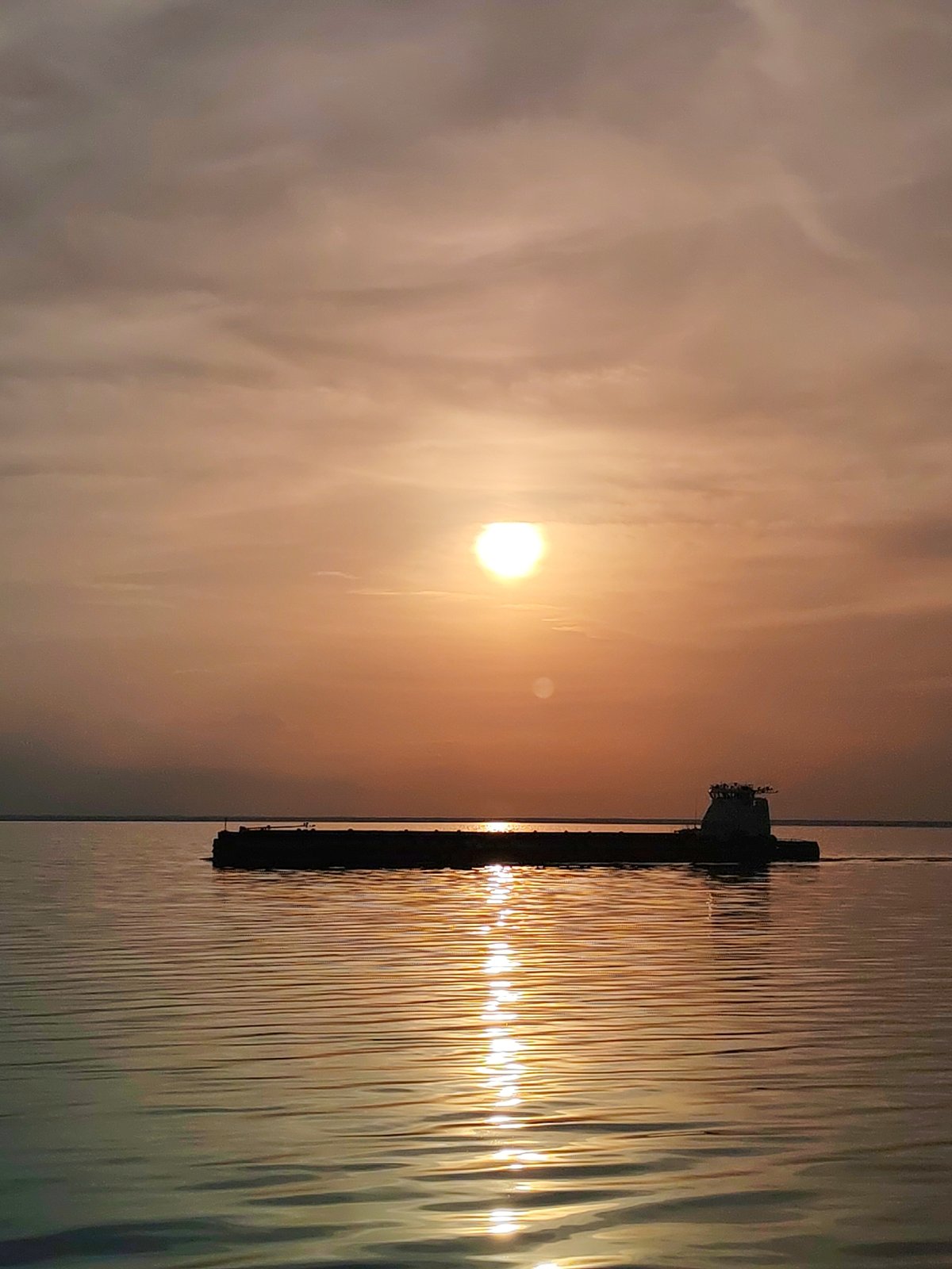 Cargo barge silhouetted against orange sky in Belozersk waters