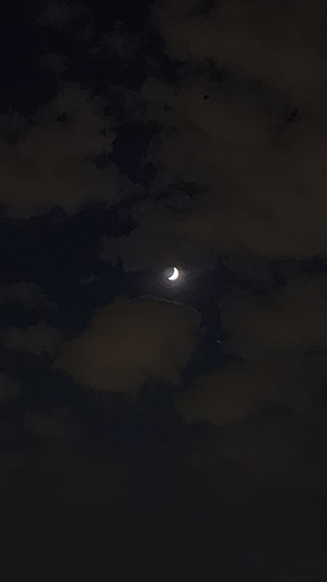 Crescent moon observed through clouds over Moscow evening sky