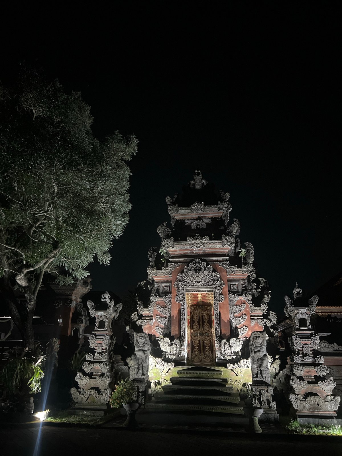 Traditional carved Balinese structure documented at night in Blahbatuh