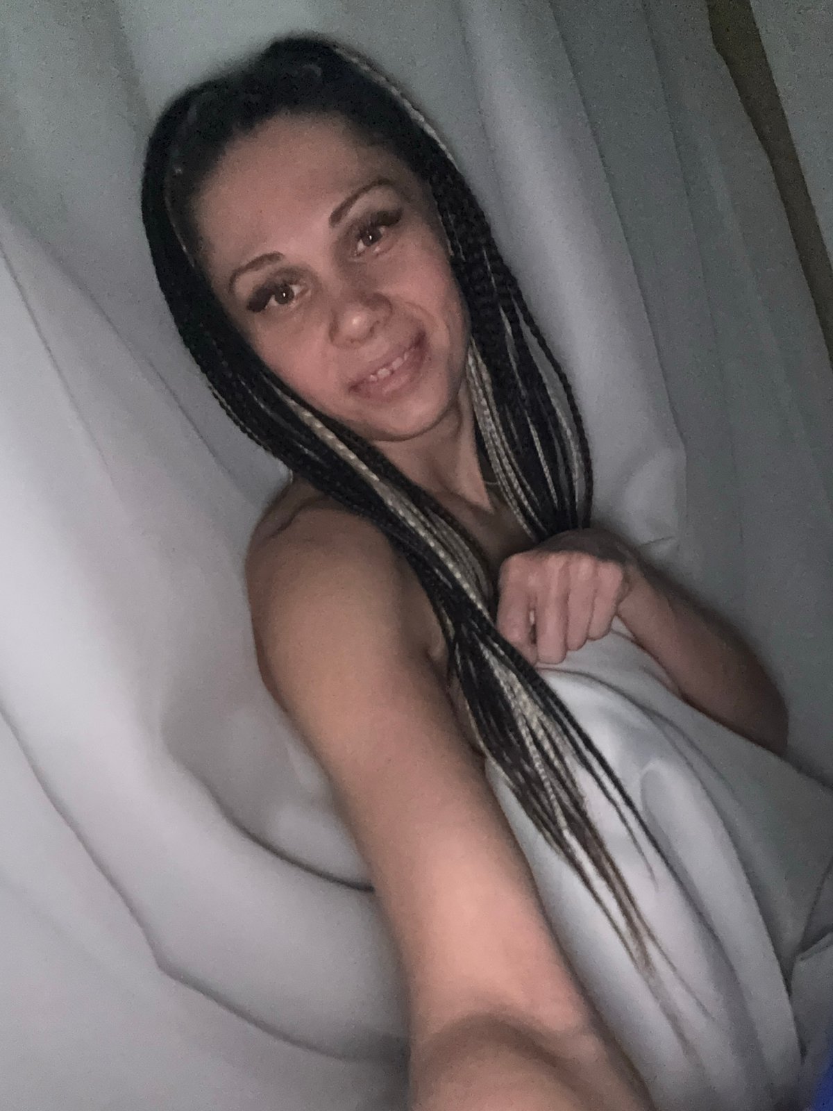 Woman with braided hair holds orange fruit while lying down