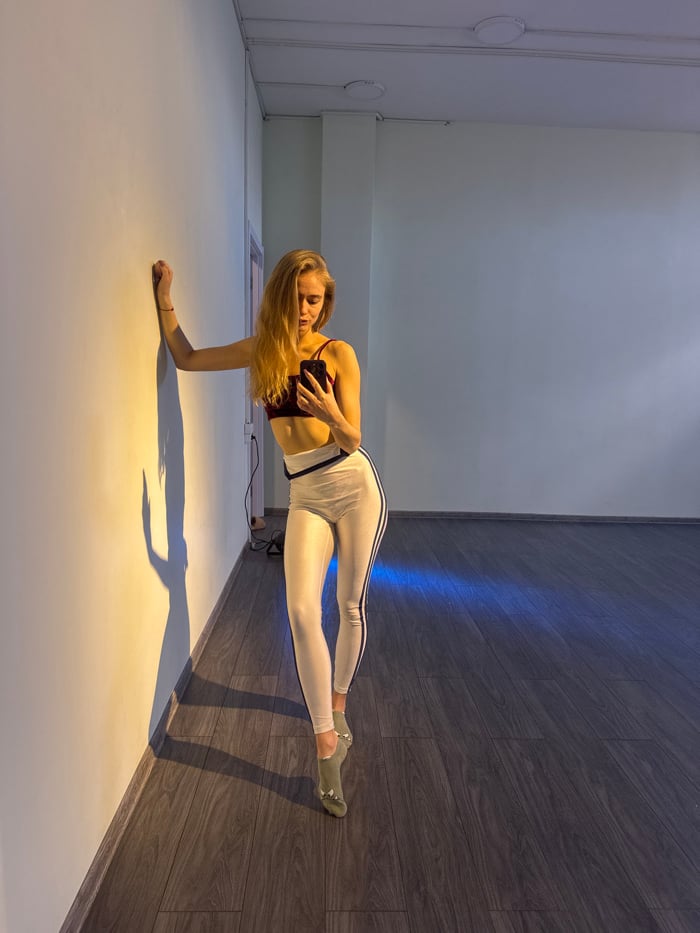 Woman takes mirror selfies in studio wearing red athletic wear