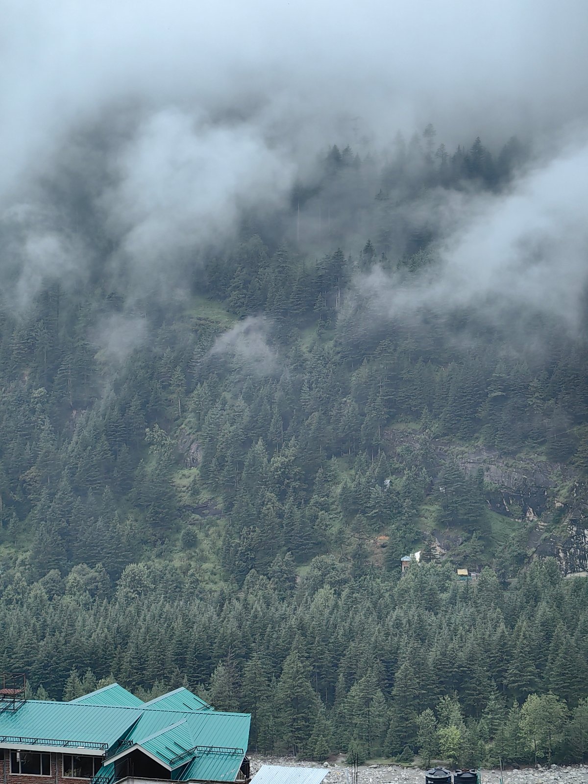 Vashisht under cloud cover, river, forest, and active construction